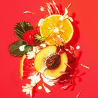 Künstlerische Aufnahme | Aufgeschnittener Pfirsich, Orange, Erdbeere und weiße Blüten auf rotem Hintergrund